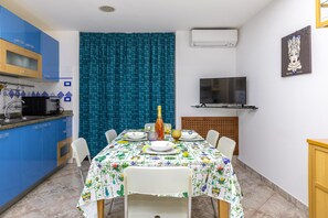 A dining area with a table set for four, a microwave, and a television on the wall. - Casa Carolina with Wi-Fi and Air Conditioning (Pozzallo)