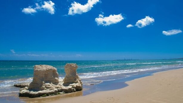 Ein Strand mit blauem Himmel und ruhigem Wasser.