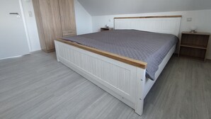 Ein Schlafzimmer mit einem Bett, einem Kleiderschrank, einem Nachttisch und einem Regal.