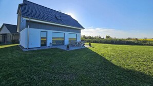 Ein modernes Haus mit großer Garage, einem weitläufigen Rasen und blauem Himmel.