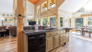 A spacious kitchen with granite countertops, wooden cabinets, and large windows. - Aspen Place 3 Bedroom Home (Bend)