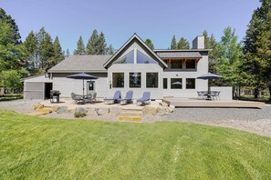 A modern two-story house with a patio area featuring outdoor furniture and umbrellas. - Aspen Place 3 Bedroom Home (Bend)