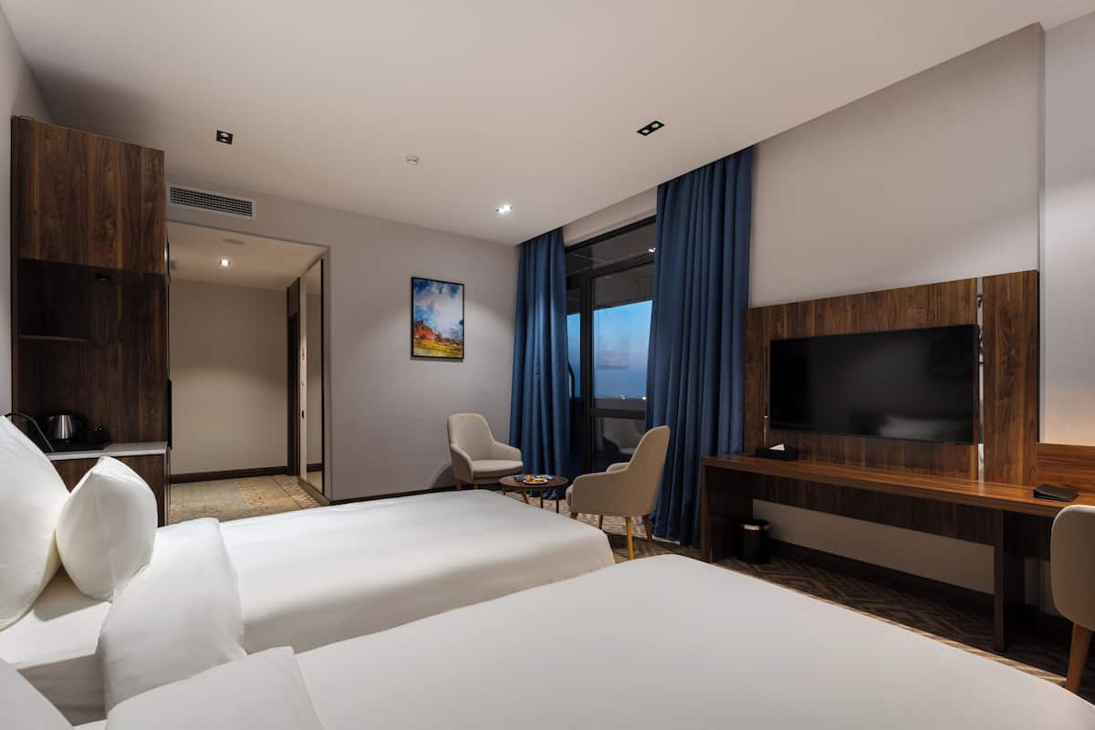 Une chambre d’hôtel avec deux lits, une télévision, un bureau et une chaise.