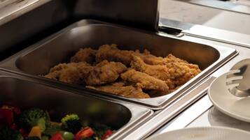 A buffet setup with various food items including fried chicken, vegetables, and a casserole dish.