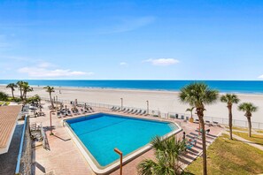 A pool area with a view of the beach, lounge chairs, and palm trees. - ☀Beachfront Condo🌴Wrap Around Private Balcony🐬Redington Towers 3A🌞Heated Pool (Redington Shores)