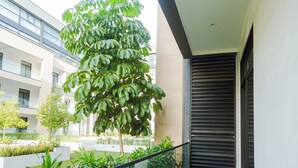 Een balkon met een tafel en stoelen, omringd door planten en uitzicht op een gebouw.