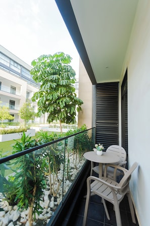 A balcony with a table and chairs, surrounded by plants and a view of a building. - Spacious One Bedroom at Embassy Gardens (Accra)