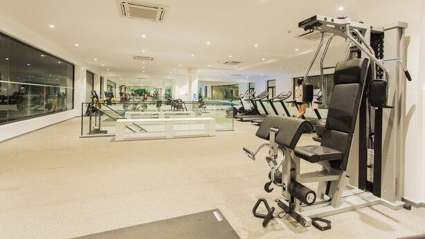 Een moderne sportschool met diverse trainingsapparaten, een glazen wand en een ruim opgezette ruimte.