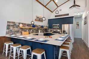A kitchen with a central island, bar stools, a ceiling fan, and a sign reading 'FOOD & FRIENDS'.