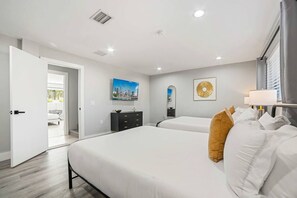 A hotel room with two beds, a dresser, a painting, and a view of a balcony.
