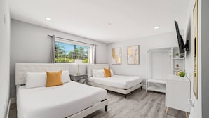 A modern hotel room with two beds, a desk, and a TV. - Heated Pool - Putting Green - 5 min From Beach! (Deerfield Beach)