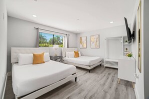 A modern hotel room with two beds, a desk, and a TV.