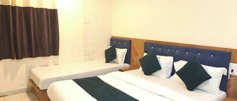 Une chambre d’hôtel avec deux lits simples, une tête de lit en bois, un climatiseur blanc et un rideau.