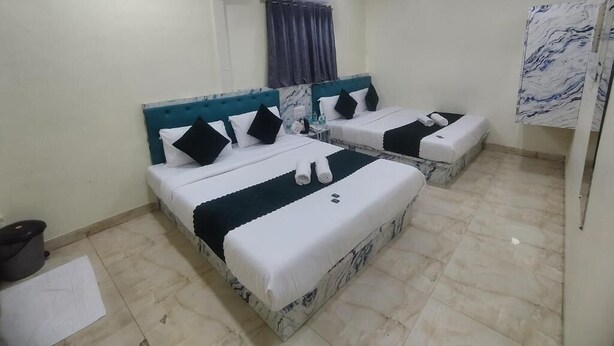 A hotel room with two beds, a marble headboard, a ceiling fan, and an air conditioning unit. - HOTEL GLOW STAR (Mumbai)
