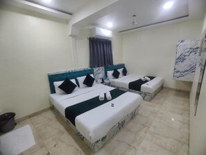 Ein Hotelzimmer mit zwei Betten, einem Marmorkopfstück, einem Deckenventilator und einer Klimaanlage.