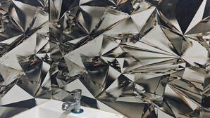 A bathroom with a sink, a mirror, and a wall with a geometric tile pattern. - HOTEL GLOW STAR (Mumbai)