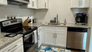 A kitchen with white cabinets, a stainless steel dishwasher, a microwave, and a stove. - 4 Blocks to Beach/Pleasure Pier-1 Block off parade route-KING Suite-Allow Pets (Galveston)