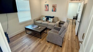 A living room with a sofa, armchair, coffee table, and artwork on the wall. - 4 Blocks to Beach/Pleasure Pier-1 Block off parade route-KING Suite-Allow Pets (Galveston)