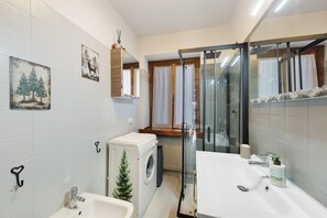 A modern bathroom with a sink, mirror, and a glass shower enclosure. - Casetta del Caregòn with Panoramic Terrace Overlooking Monte Pelmo, UNESCO Dolomites (VODO CADORE)