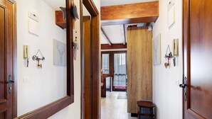 Un pasillo con puertas de madera, un taburete pequeño y adornos en la pared.