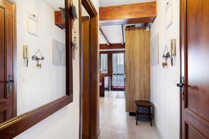 Un pasillo con puertas de madera, un taburete pequeño y adornos en la pared.