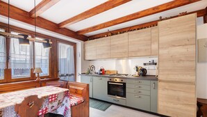 Una cocina con vigas de madera, una mesa con mantel y armarios.
