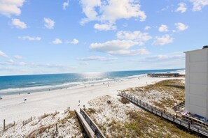 A beach with a wooden boardwalk, a pier, and a building on the right. - Island Sunrise 466 | 2 Bed 2 Bath Sleeps 7 (Gulf Shores)