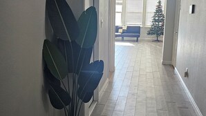 Un pasillo con una planta en maceta, un árbol de Navidad y un sofá azul al fondo.