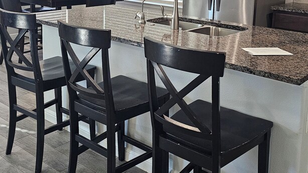 Una cocina moderna con una isla central, taburetes de bar, electrodomésticos de acero inoxidable y salpicadero.