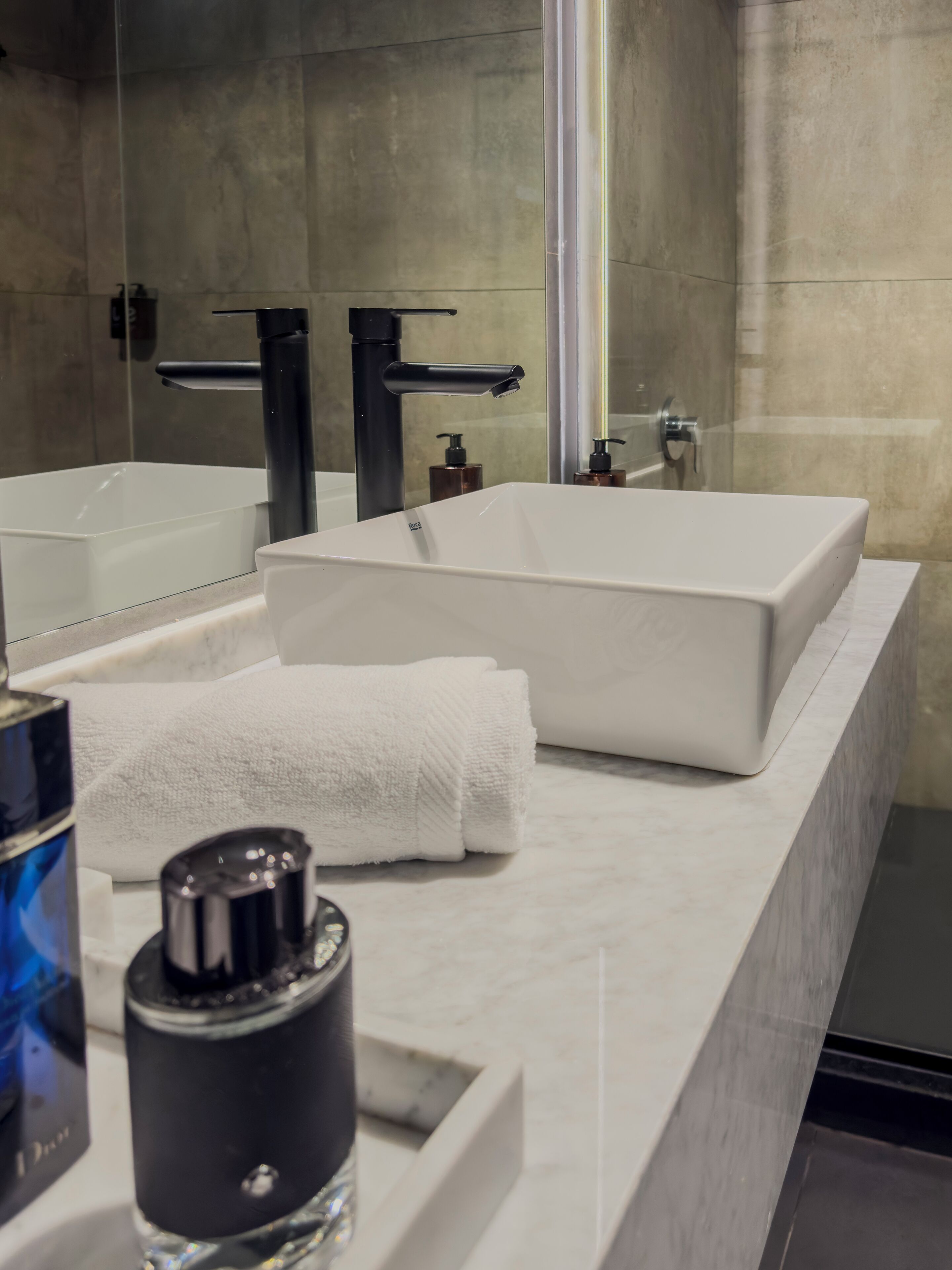 A modern bathroom with a large mirror, two sinks, and a shower.