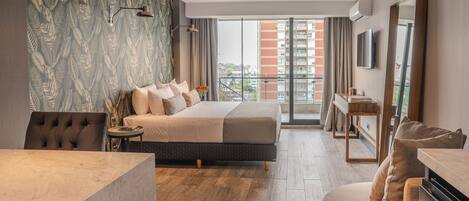 Une chambre d’hôtel moderne dotée d’un grand lit, d’un bureau, d’un canapé et d’un balcon offrant une vue sur la ville.