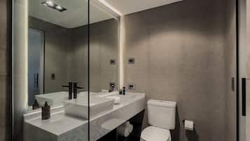 Un baño moderno con un espejo grande, dos lavamanos, un inodoro y una zona de ducha.