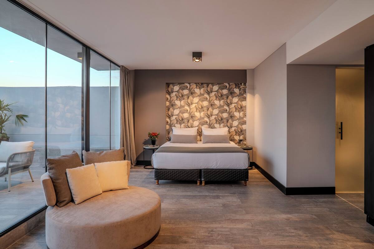 Een moderne slaapkamer met een groot bed, een zitgedeelte met ronde vormen, en een muur met een steenmotief.