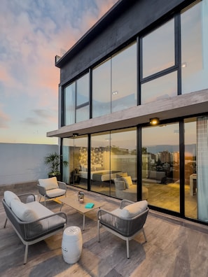A modern outdoor living space with a glass-enclosed patio, wicker furniture, and a view of the cityscape. - Casa Joseph Libertador (Buenos Aires)