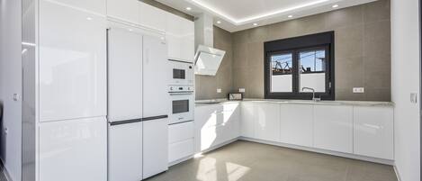 A modern kitchen with white cabinetry, a built-in oven, and a microwave.