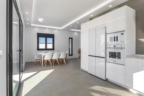 A modern kitchen with white cabinetry, a built-in oven, and a dining area with a table and chairs. - Vacation Home 'Paraíso' with Private Pool, Wi-Fi and Air Conditioning (Chiclana de la Frontera)