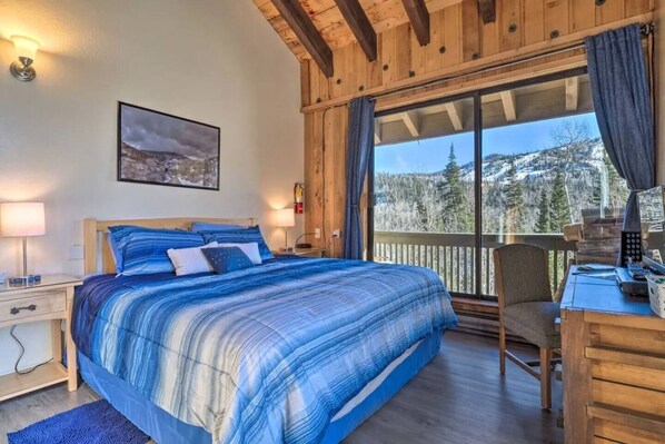 Un dormitorio con una cama grande, un escritorio y vistas a un paisaje nevado.