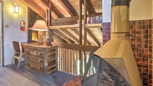 A rustic interior with a wooden desk, a lamp, a fireplace, and a staircase. - Aspen View Lodge 4 bed/3 ba, Sauna, W/D, Views (Brian Head)
