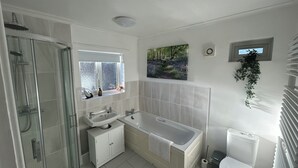 Ein modernes Badezimmer mit einer gläsernen Duschkabine, einem Doppelwaschtisch, einer freistehenden Badewanne und einem WC.