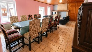 A dining area with a long table, floral-patterned chairs, and a wooden ceiling.