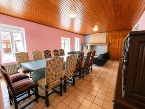 Zona pranzo con un tavolo lungo, sedie a motivi floreali e soffitto in legno.