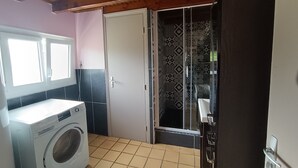 A compact laundry area with a washing machine, a door with patterned glass, and a tiled floor.