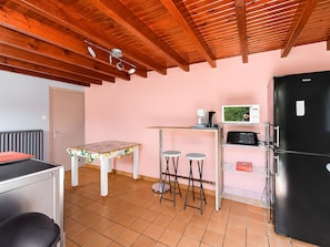 Une cuisine compacte avec un plafond en bois, un réfrigérateur, un four à micro-ondes et une petite table avec des tabourets.