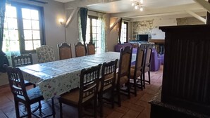 A dining area with a table, chairs, and a kitchen in the background.
