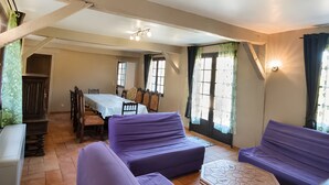 A room with purple sofas, a dining table, and chairs.