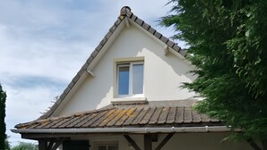 A house with a tiled roof, a covered porch, a window, and a door.