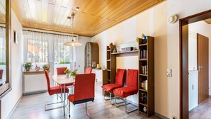 Ein modernes Wohnzimmer mit Holzboden, einem Essbereich mit Tisch und Stühlen sowie einem Bücherregal.