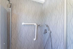 Ducha con pasamanos, cabezal de ducha de mano y grifo empotrado.