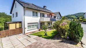 Ein modernes, zweigeschossiges Haus mit Balkon, Garage und einem gepflegten Garten.