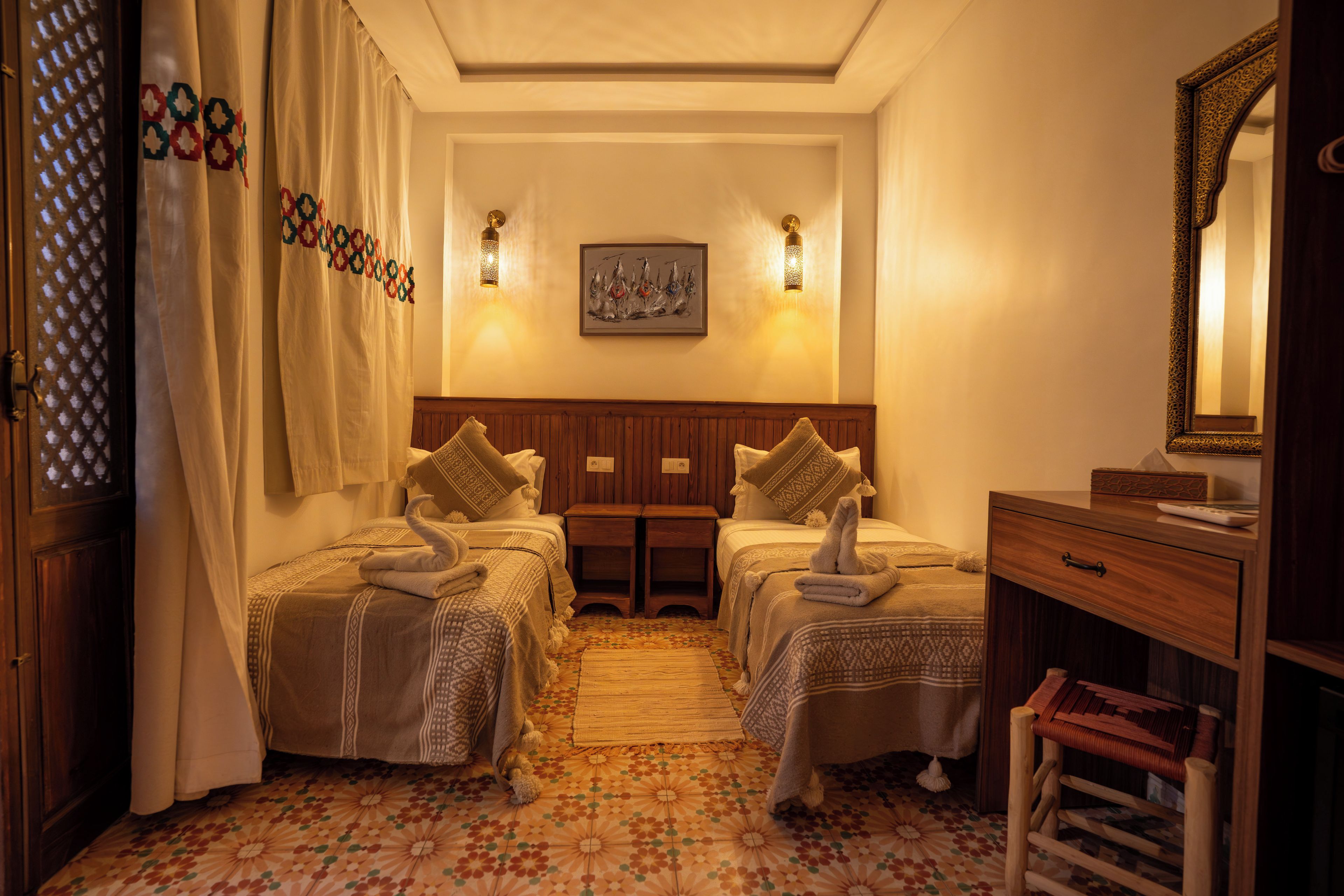 Habitación de hotel con dos camas, un aparador de madera, un espejo y un suelo estampado.